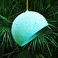 turquoise hanging lamp globe with green plants in the background